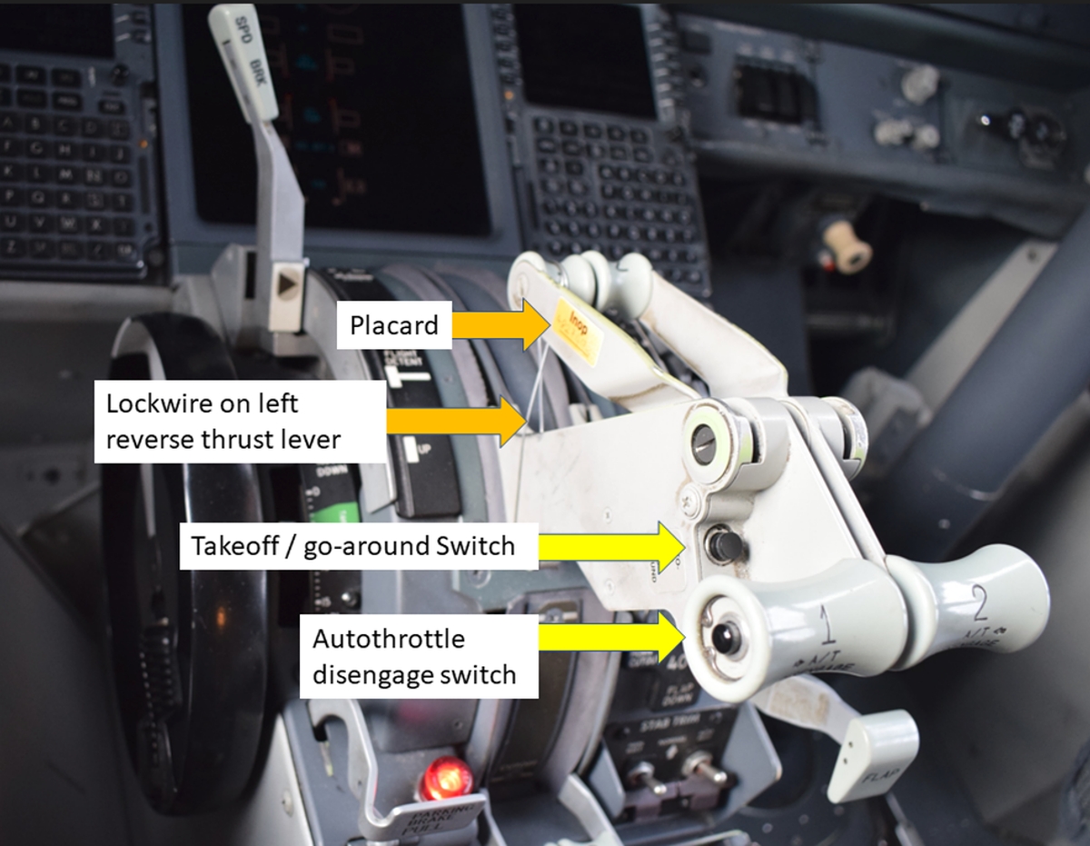 Figure 1. The layout of the control stand in the occurrence aircraft, showing the lockwired left reverse thrust lever, placard, takeoff/go-around switch, and autothrottle disengage switch (Source: TSB) Figure 1. The layout of the control stand in the occurrence aircraft, showing the lockwired left reverse thrust lever, placard, takeoff/go-around switch, and autothrottle disengage switch (Source: TSB)
